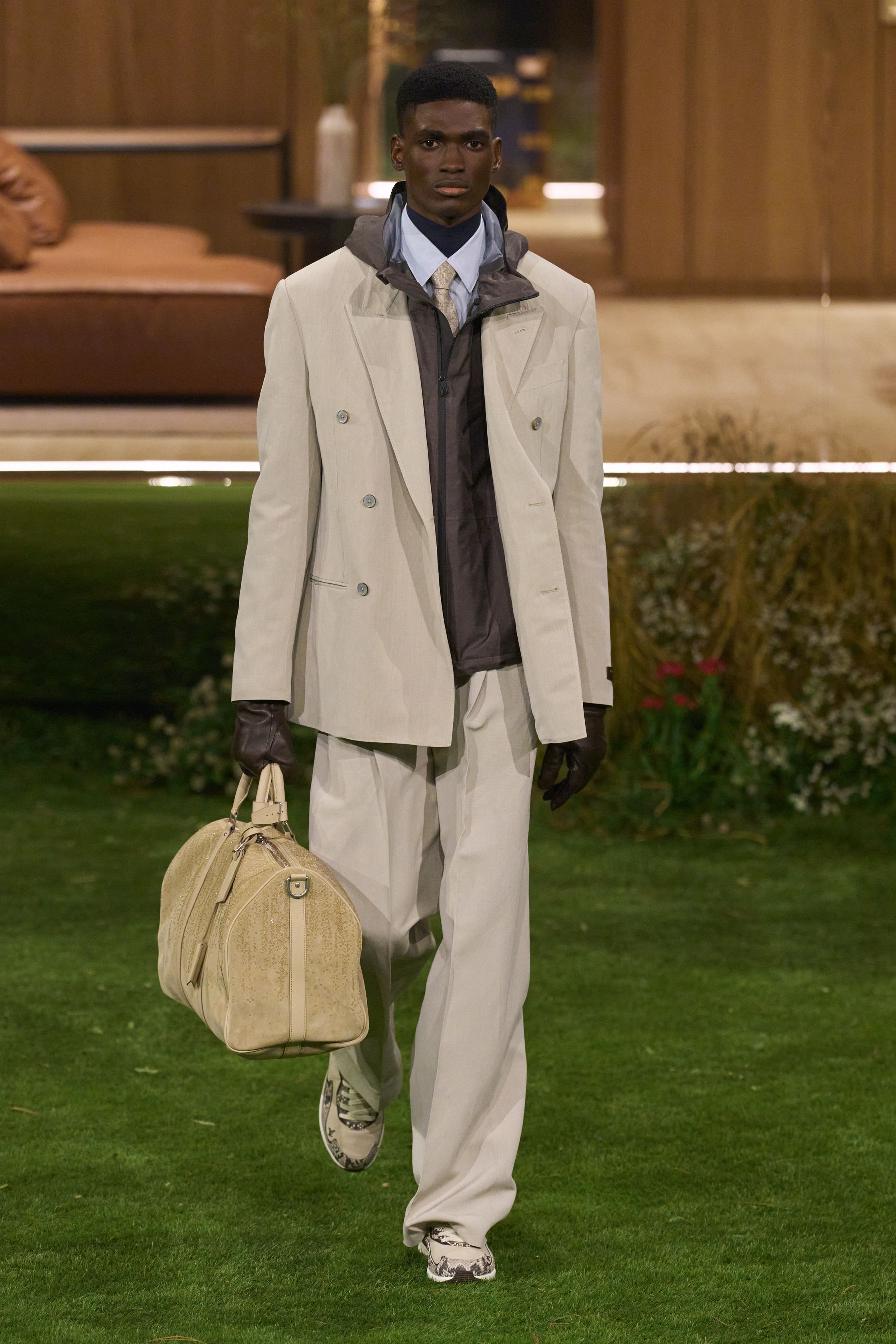 Louis Vuitton 26FW 男装以“当代绅士的旅行状态”为核心，在花园式场景中展开一场关于移动、身份与功能的叙事。功能夹克、细致西装、学院感针织与标志性包袋并行出现，色彩回归卡其、橄榄绿、灰褐与深红，呈现出低调却高度可穿的奢华现实主义。系列强化了“穿着中的生活感”，将品牌传统的旅行基因转译为更克制、更日常的现代衣橱方案-顽石频道趋势研究